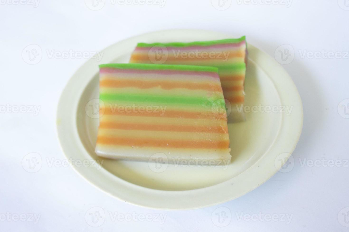 lapis cake or roti lapis or layer cake or lapis legit served in little plate isolated on white background made from rice flour, starch, coconut milk, sugar, salt and coloring photo