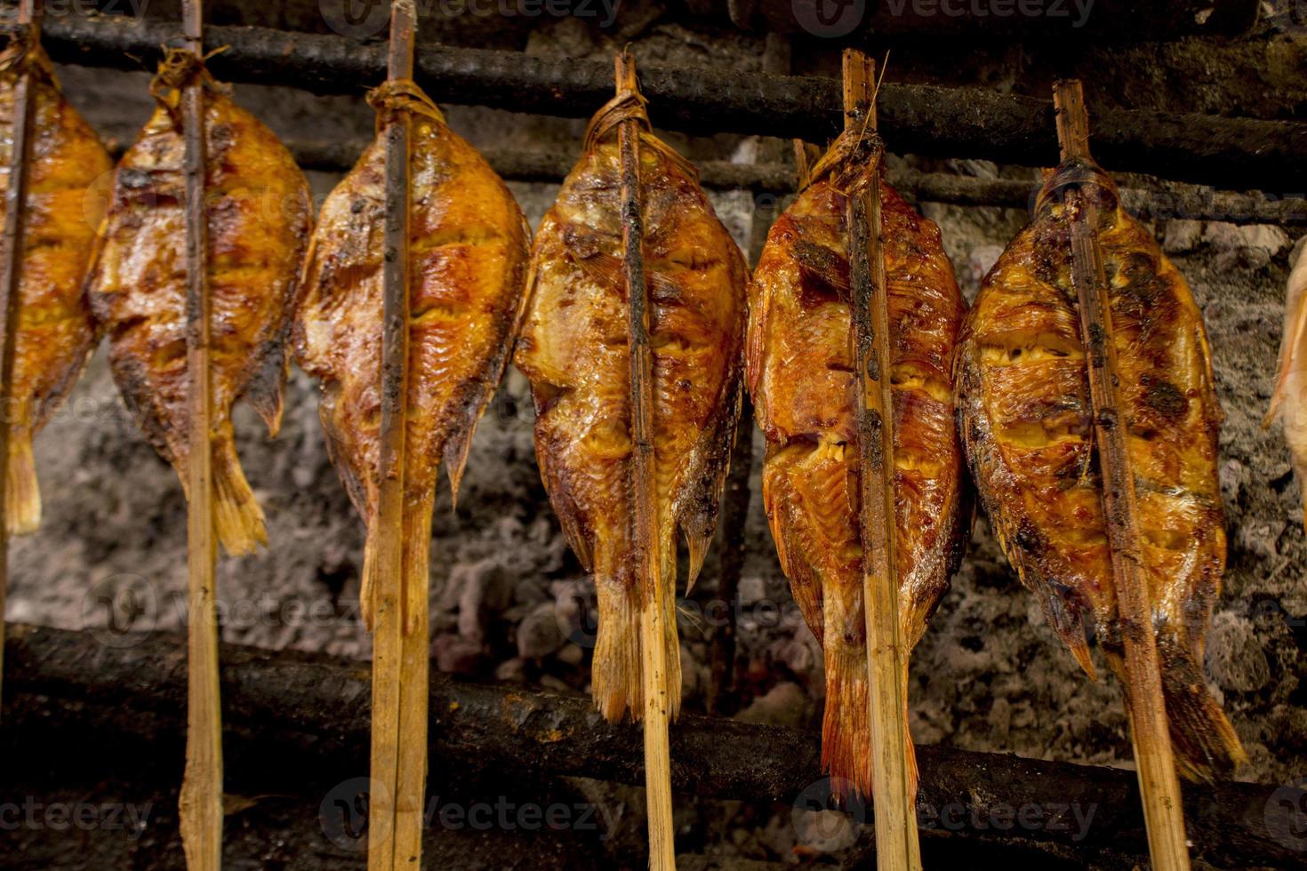 pescado a la parrilla, pescado a la parrilla tilapia del nilo a la parrilla sobre carbón caliente foto