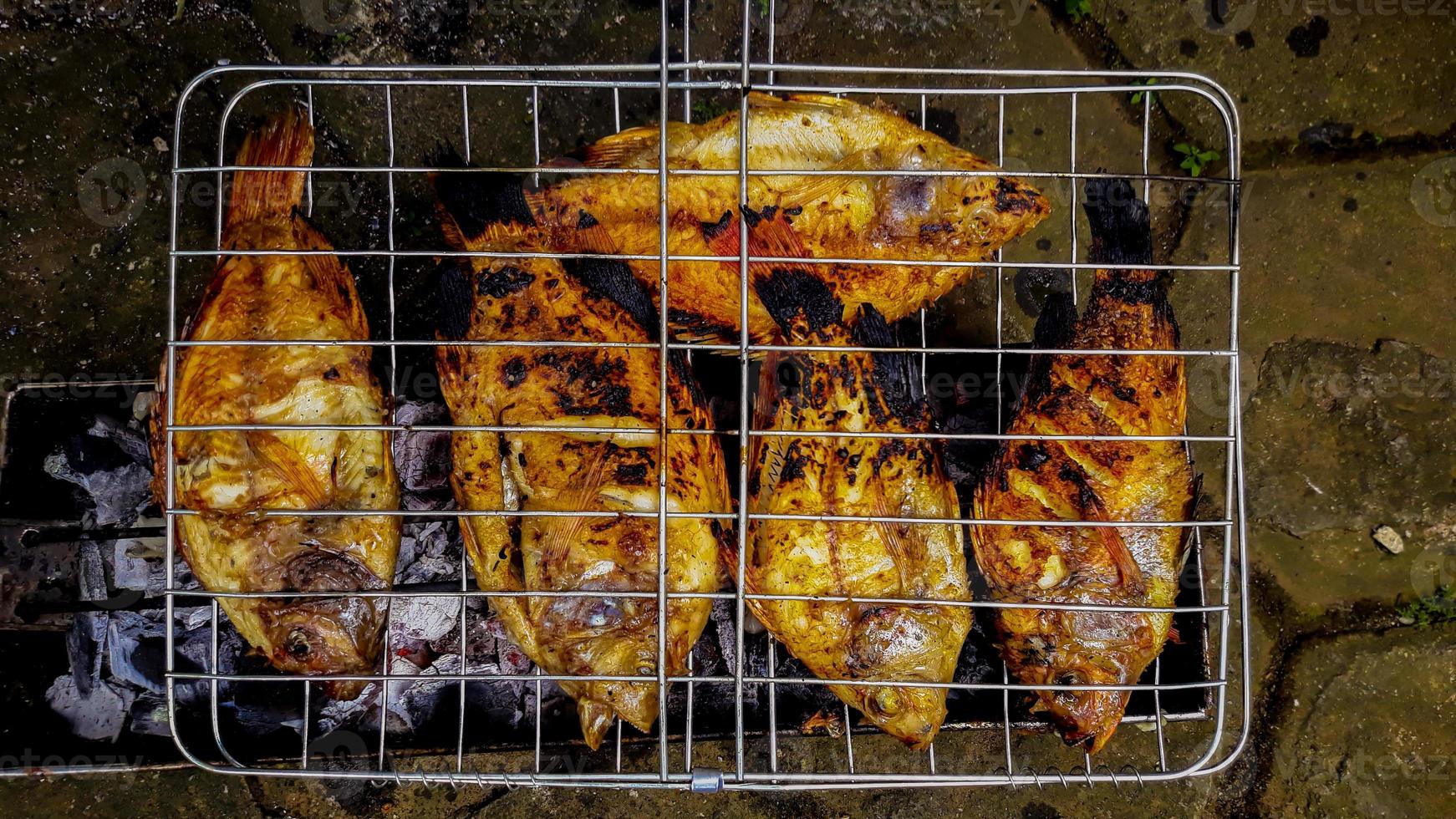 pescado a la parrilla, pescado a la parrilla tilapia del nilo a la parrilla sobre carbón caliente foto