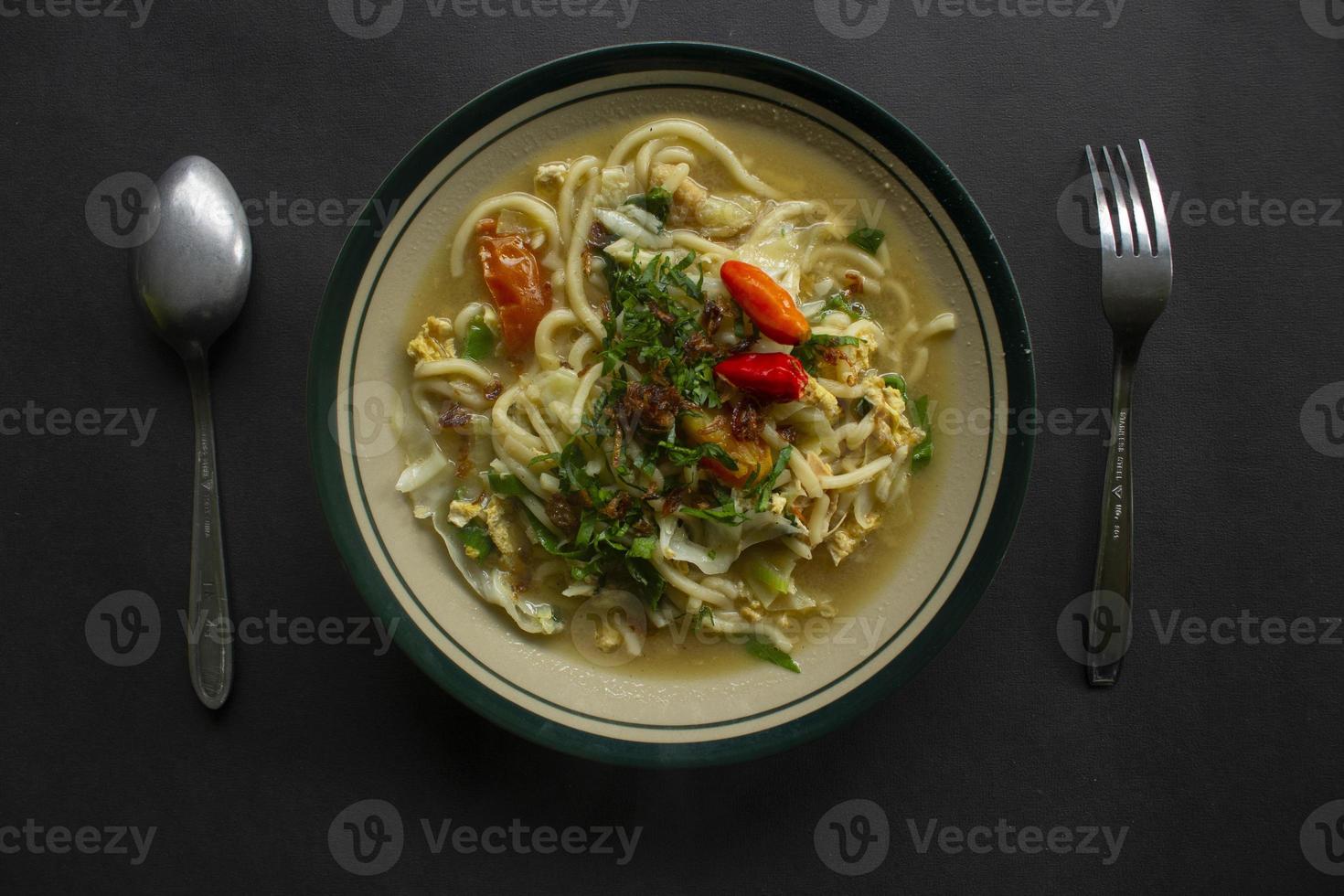 Mie godog Jawa or bakmi jawa or java noodle or Mie rebus or boiled noodles with spoon and fork. Indonesian traditional street food noodles from java, indonesia on white backgroud photo