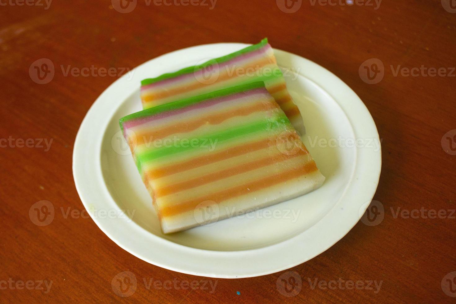 lapis cake or roti lapis or layer cake or lapis legit served in little plate isolated on white background made from rice flour, starch, coconut milk, sugar, salt and coloring photo