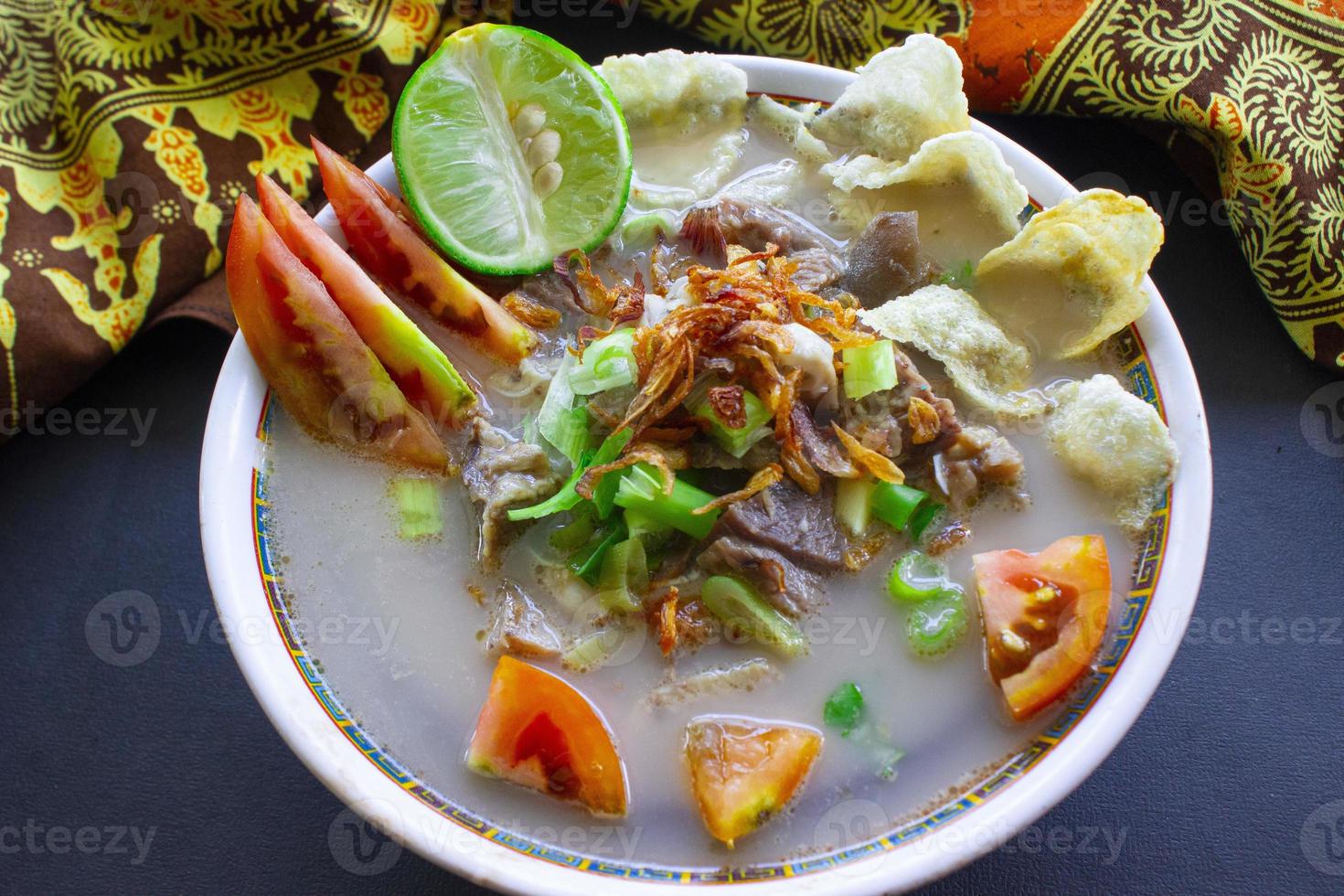 sop kaki kambing a traditional food from Betawi, Jakarta Indonesia, made from mutton or lamb, offal, spices. isolated on black background.This food is like lamb stew on black background photo