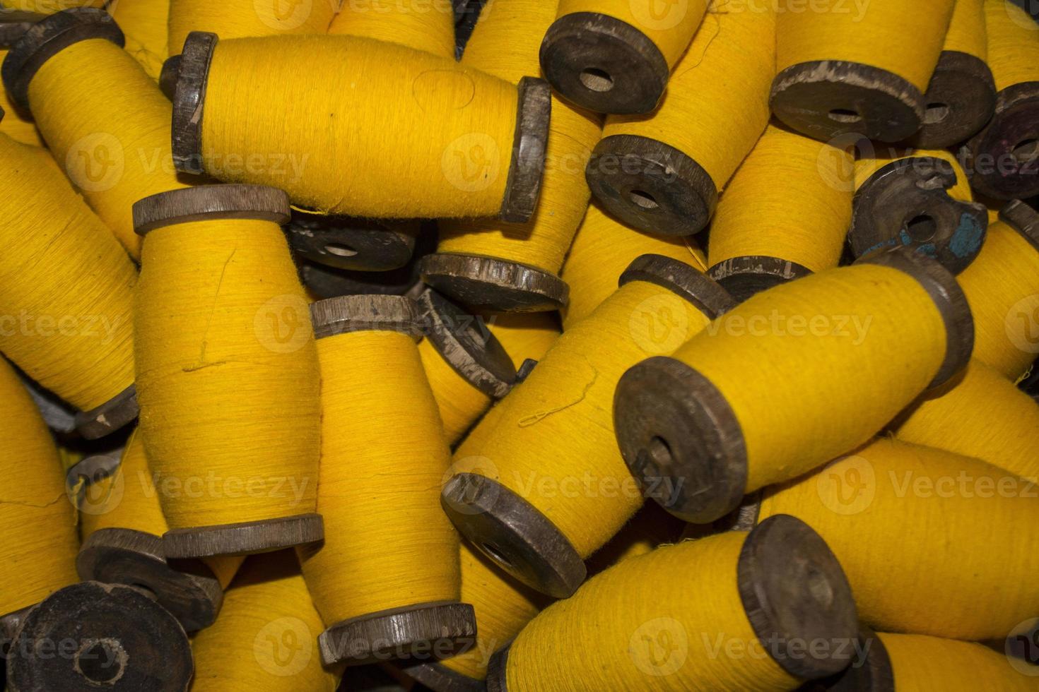 large grup yellow yarn on wood spool, yarn on tube, a collection of yellow threads on spool, which will be fabricated. yellow string. yellow thread. photo