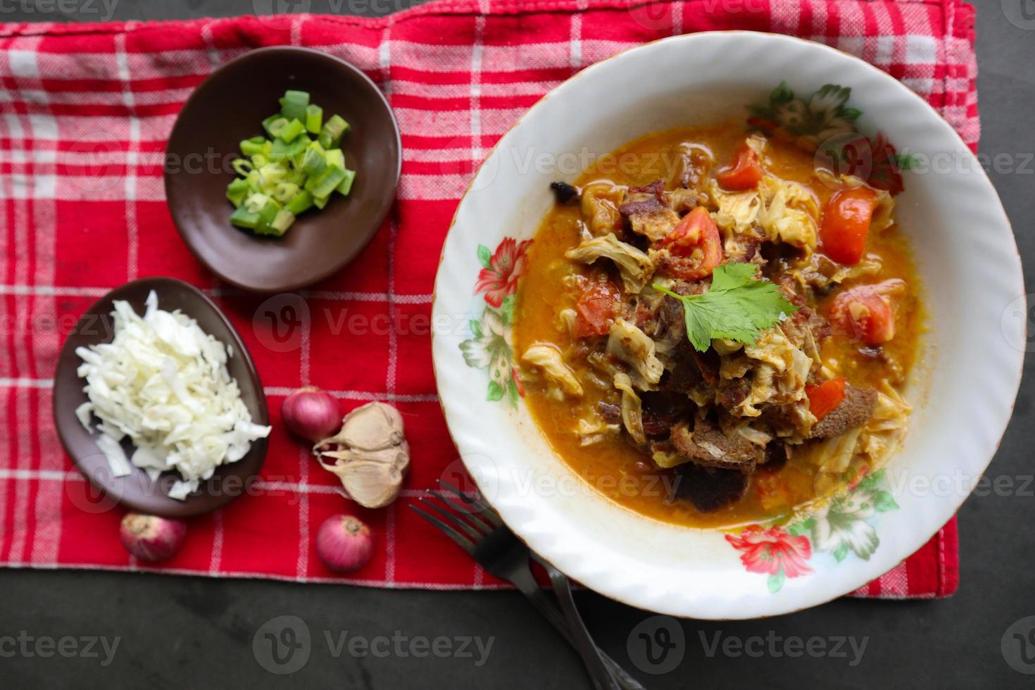 Goat Curry or gulai kambing, food from asia. Delicious goat meat curry served in a bowl.served with tomato, seasoning, celery and cabbage photo