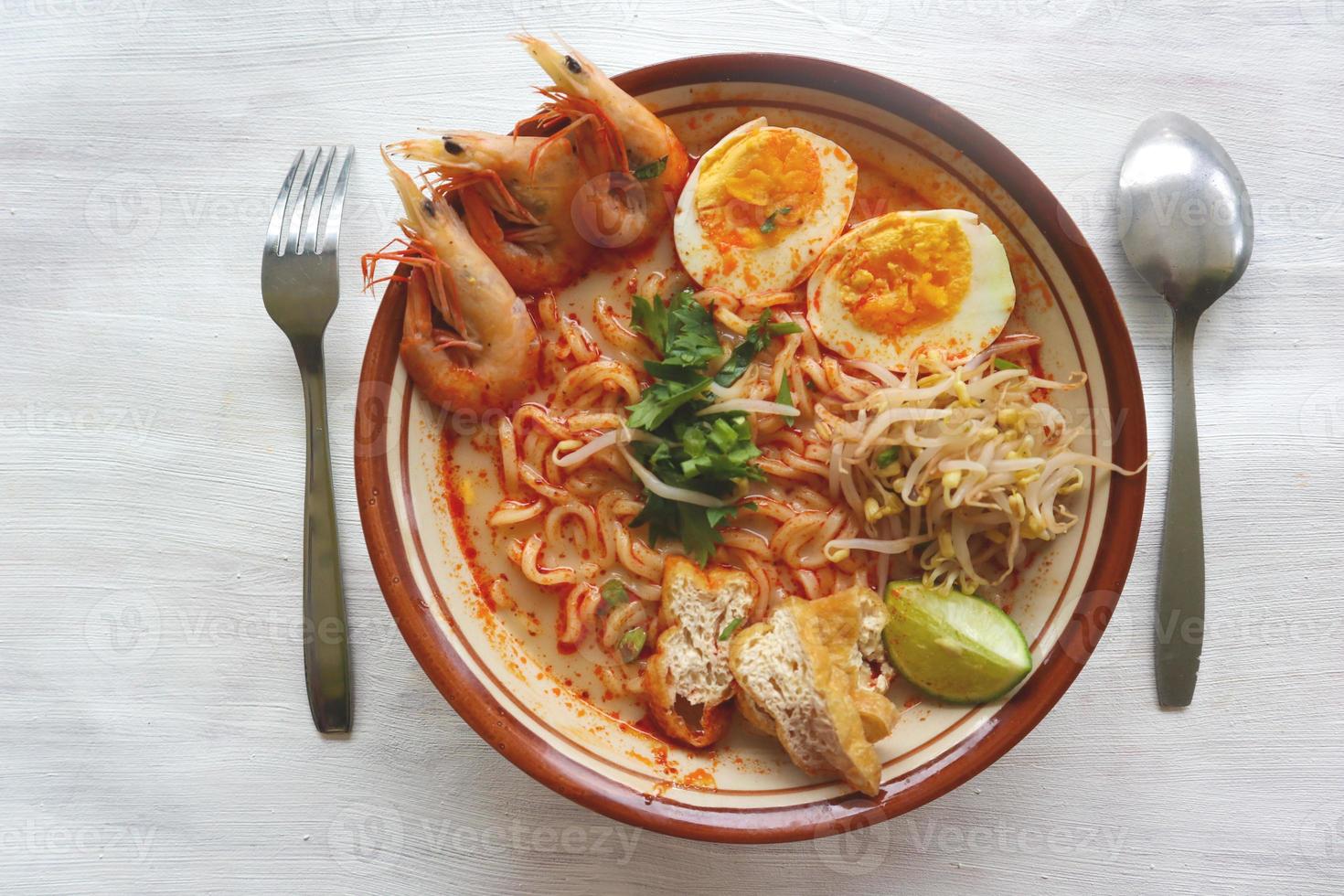 laksa, laksa curry made from vermicelli, noodles, bean sprouts, egg, tofu lime, and shrimp with a spicy soup sauce that is rich in spices. laksa served on bowl, isolated on white background. photo