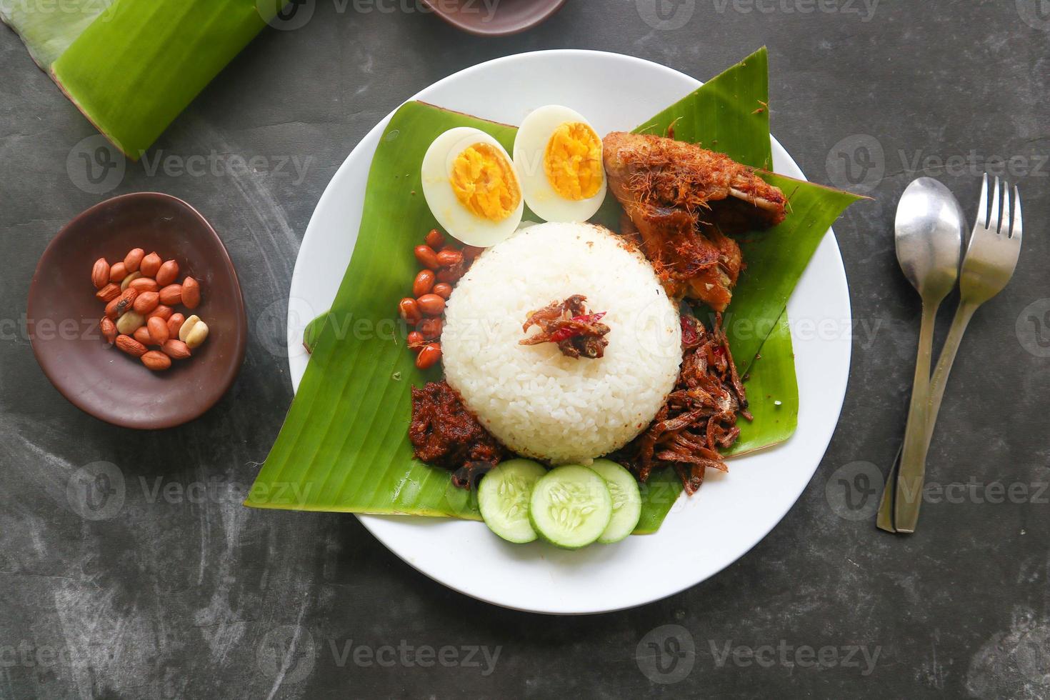 nasi lemak, is traditional malay made boiled eggs, beans, anchovies, chili sauce, cucumber. from dish served on a banana leaf photo