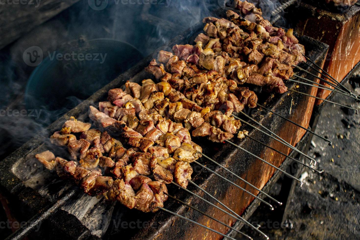 sate klatak o sate kambing o satay de cabra, cordero, cordero o carne de cabra satay con ingrediente de carbón en fuego rojo asado por personas, indonesia cocinando satay. con enfoque selectivo foto