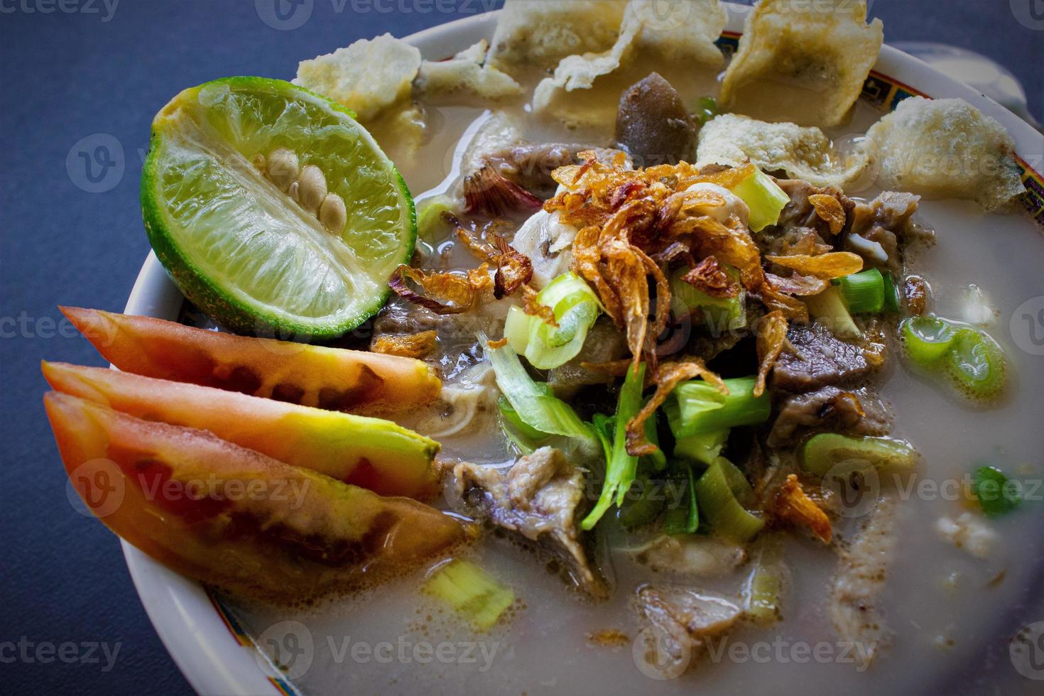 sop kaki kambing a traditional food from Betawi, Jakarta Indonesia, made from mutton or lamb, offal, spices. isolated on black background.This food is like lamb stew on black background photo