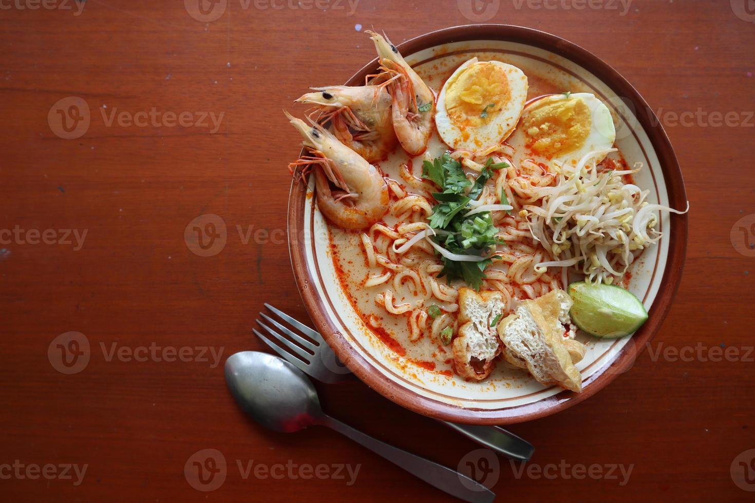 laksa, laksa curry made from vermicelli, noodles, bean sprouts, egg, tofu lime, and shrimp with a spicy soup sauce that is rich in spices. laksa served on bowl, isolated on white background. photo
