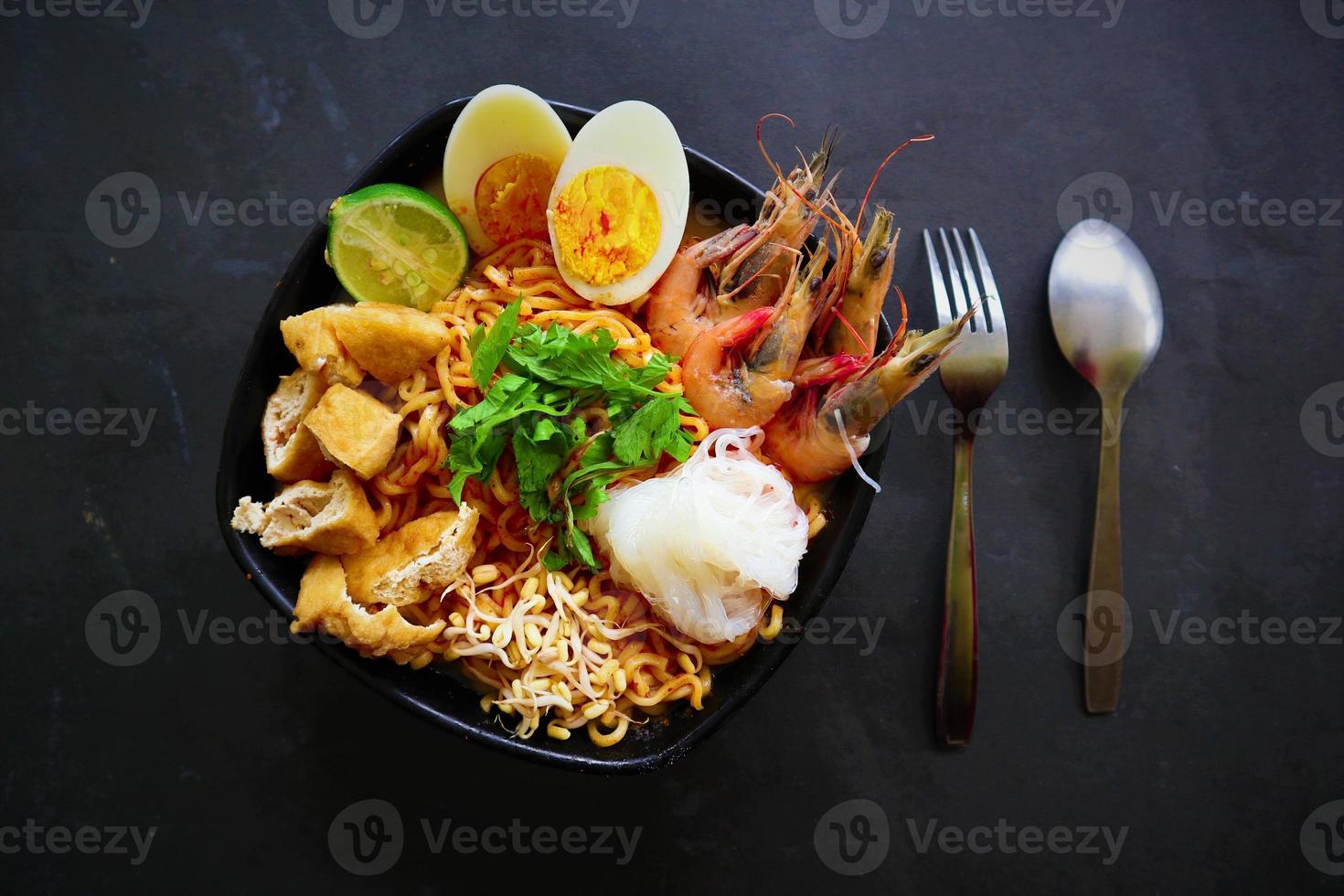 laksa, laksa curry made from vermicelli, noodles, bean sprouts, egg, tofu lime, and shrimp with a spicy soup sauce that is rich in spices. laksa served on bowl, isolated on white background. photo