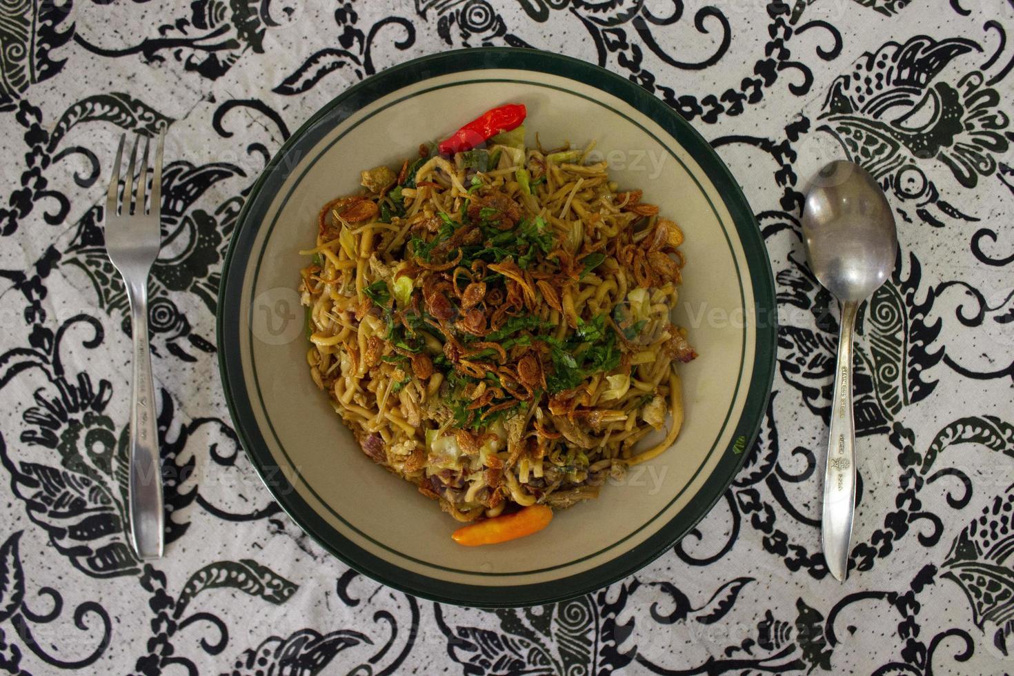 Mie Goreng Jawa or bakmi jawa or java noodle with spoon and fork. Indonesian traditional street food noodles from central java or Yogyakarta, indonesia on white background photo