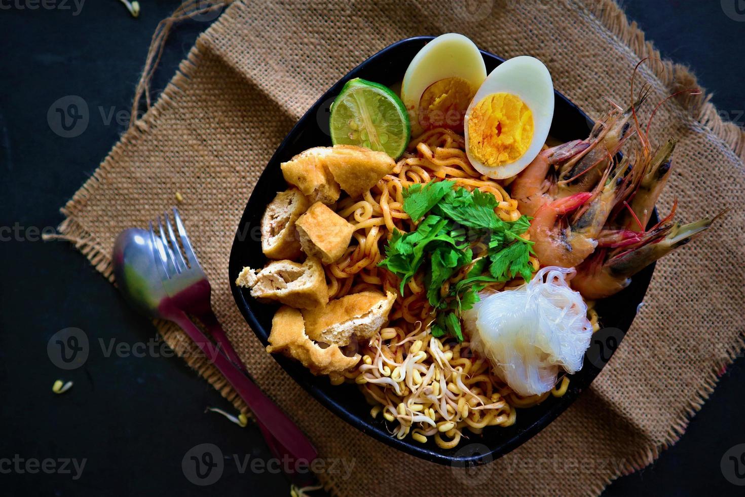 laksa, laksa curry made from vermicelli, noodles, bean sprouts, egg, tofu lime, and shrimp with a spicy soup sauce that is rich in spices. laksa served on bowl, isolated on white background. photo