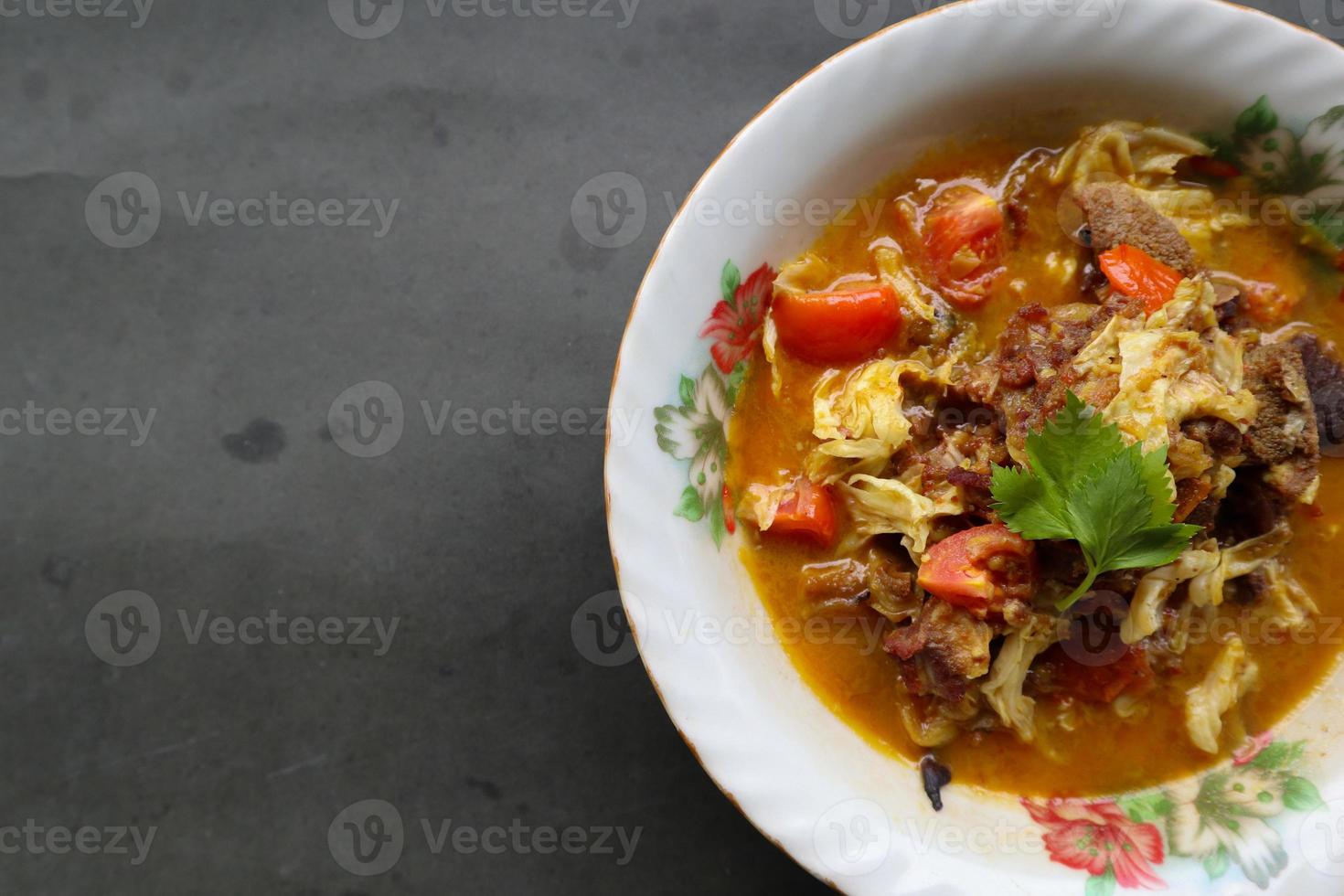 Goat Curry or gulai kambing, food from asia. Delicious goat meat curry served in a bowl.served with tomato, seasoning, celery and cabbage photo