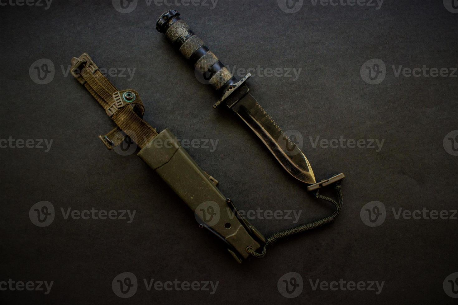 dark black military knife on black background photo