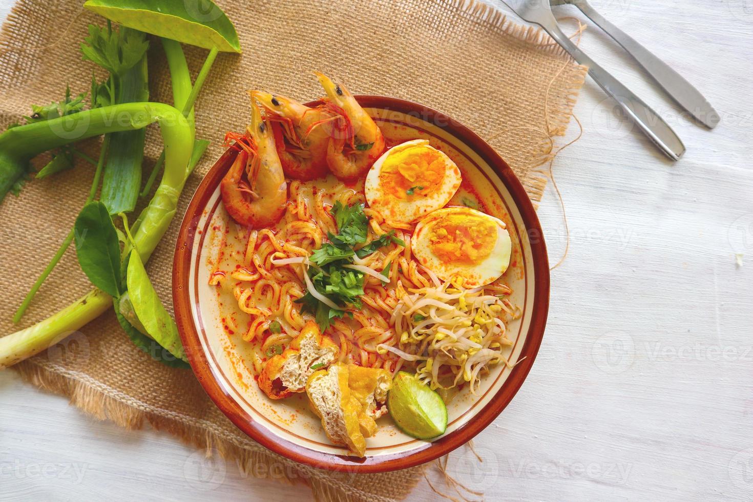 laksa, laksa curry made from vermicelli, noodles, bean sprouts, egg, tofu lime, and shrimp with a spicy soup sauce that is rich in spices. laksa served on bowl, isolated on white background. photo