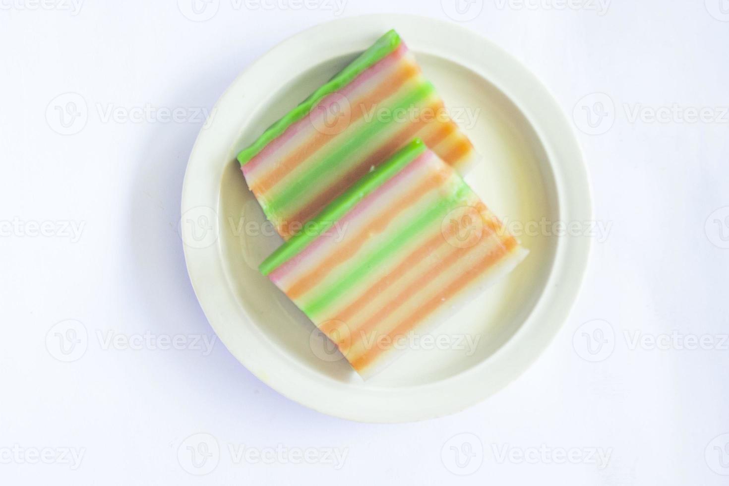 lapis cake or roti lapis or layer cake or lapis legit served in little plate isolated on white background made from rice flour, starch, coconut milk, sugar, salt and coloring photo