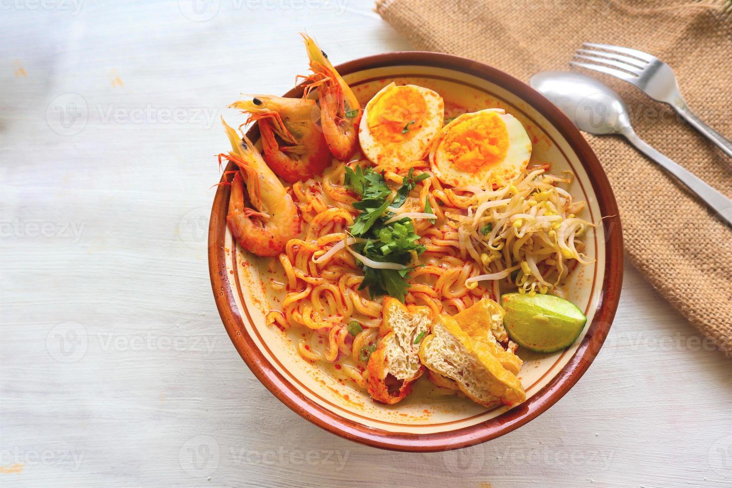 laksa, laksa curry made from vermicelli, noodles, bean sprouts, egg, tofu lime, and shrimp with a spicy soup sauce that is rich in spices. laksa served on bowl, isolated on white background. photo