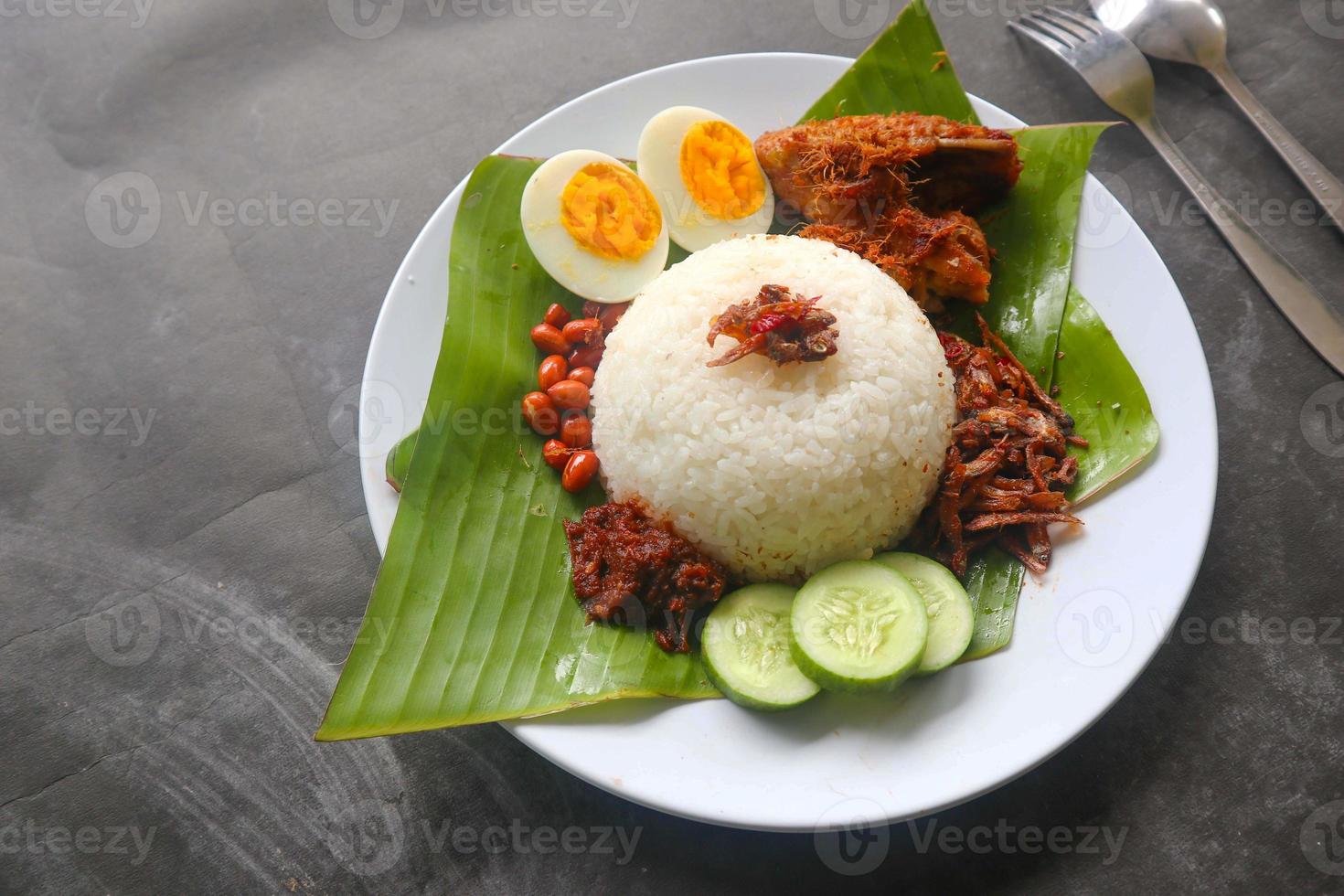 nasi lemak, is traditional malay made boiled eggs, beans, anchovies, chili sauce, cucumber. from dish served on a banana leaf photo