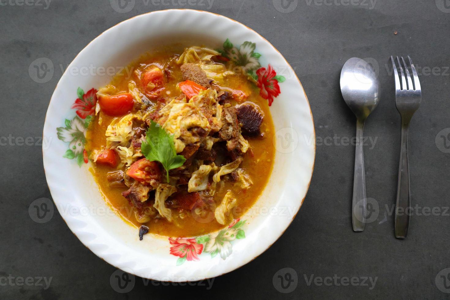 Goat Curry or gulai kambing, food from asia. Delicious goat meat curry served in a bowl.served with tomato, seasoning, celery and cabbage photo