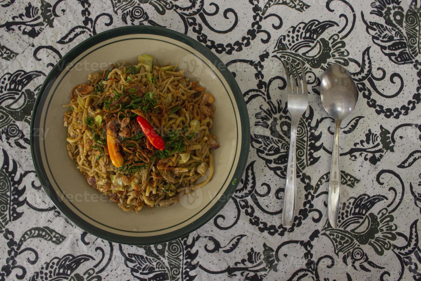 Mie Goreng Jawa or bakmi jawa or java noodle with spoon and fork. Indonesian traditional street food noodles from central java or Yogyakarta, indonesia on white background photo