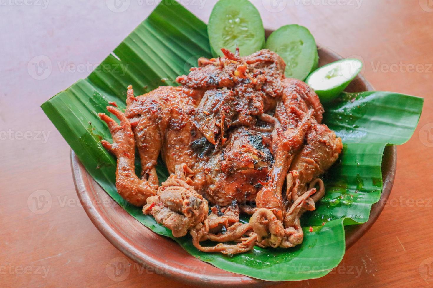 grilled chicken or ayam bakar with cucumber slash served on banana leaf and plate. ayam bakar is traditional grilled chicken from indonesia photo