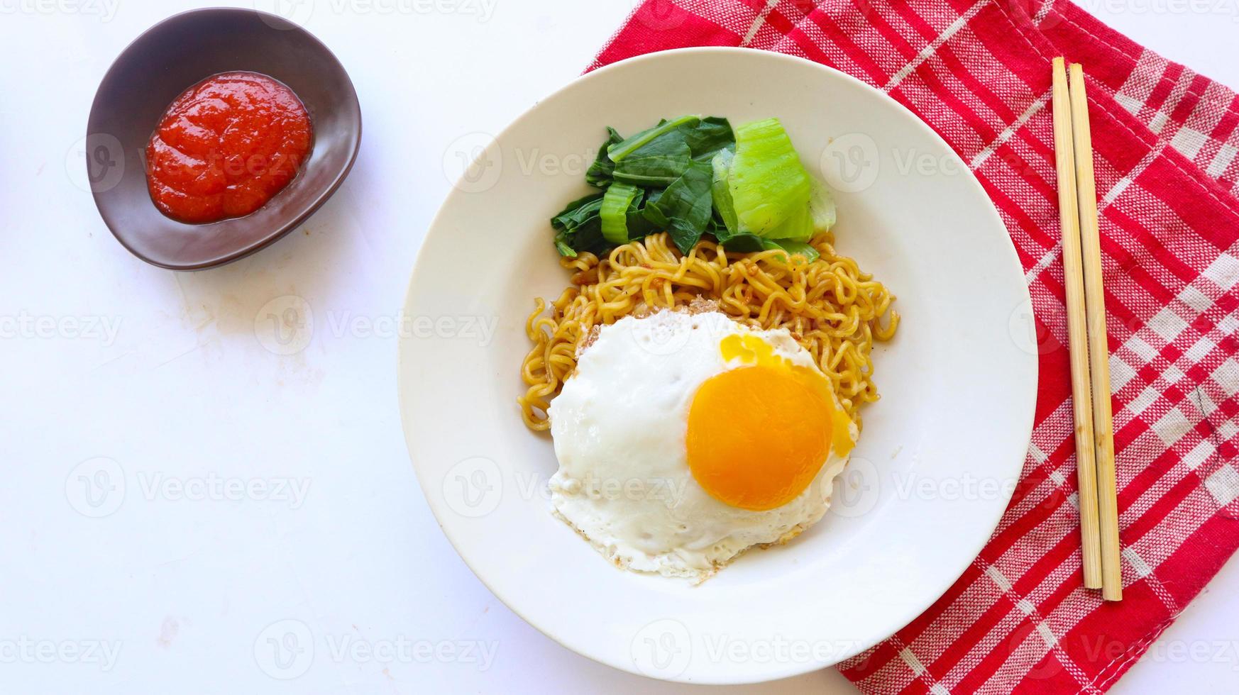 instant noodles served with egg fried and mustard greens on plate. instant fried noodle indomie photo