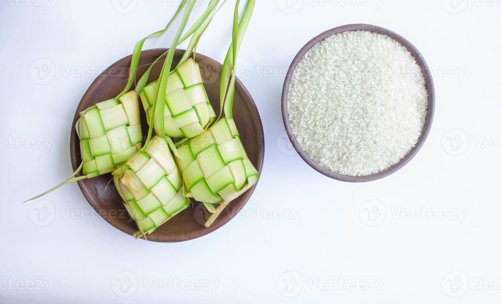 ketupat in earthenware plate isolated on white background. Ketupat ,Rice Dumpling is food served when idhul fitri eid mubarak in Indonesia, made from rice wrapped in young coconut leaves, janur photo