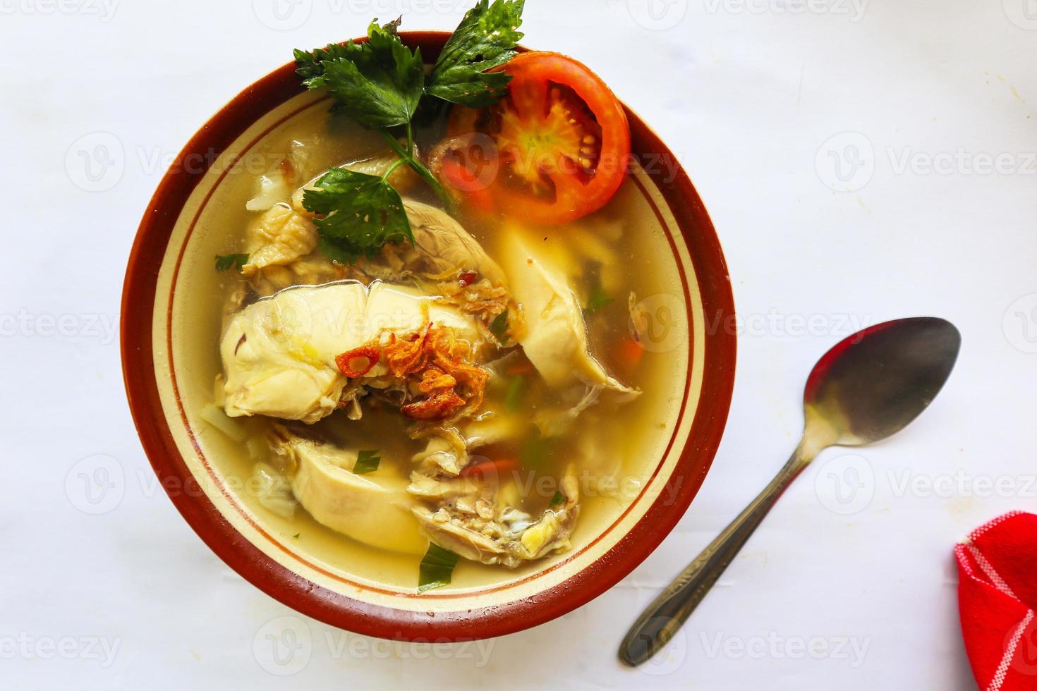 Chicken soup served with vegetables, tomatoes, celery in a bowl, spoon and fork. with black background photo