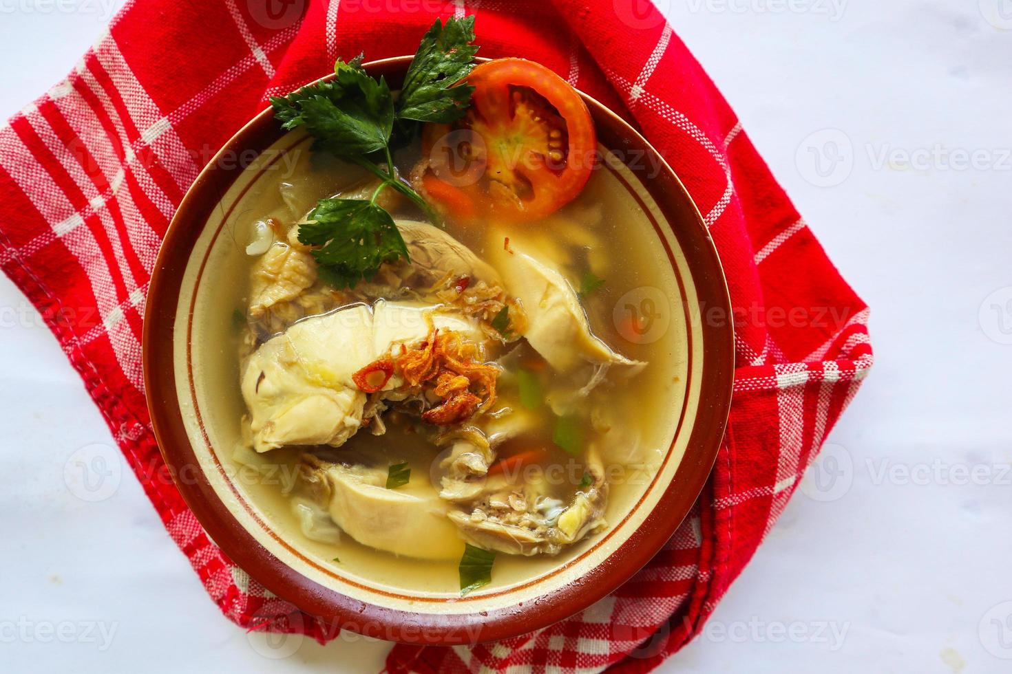 Chicken soup served with vegetables, tomatoes, celery in a bowl, spoon and fork. with black background photo