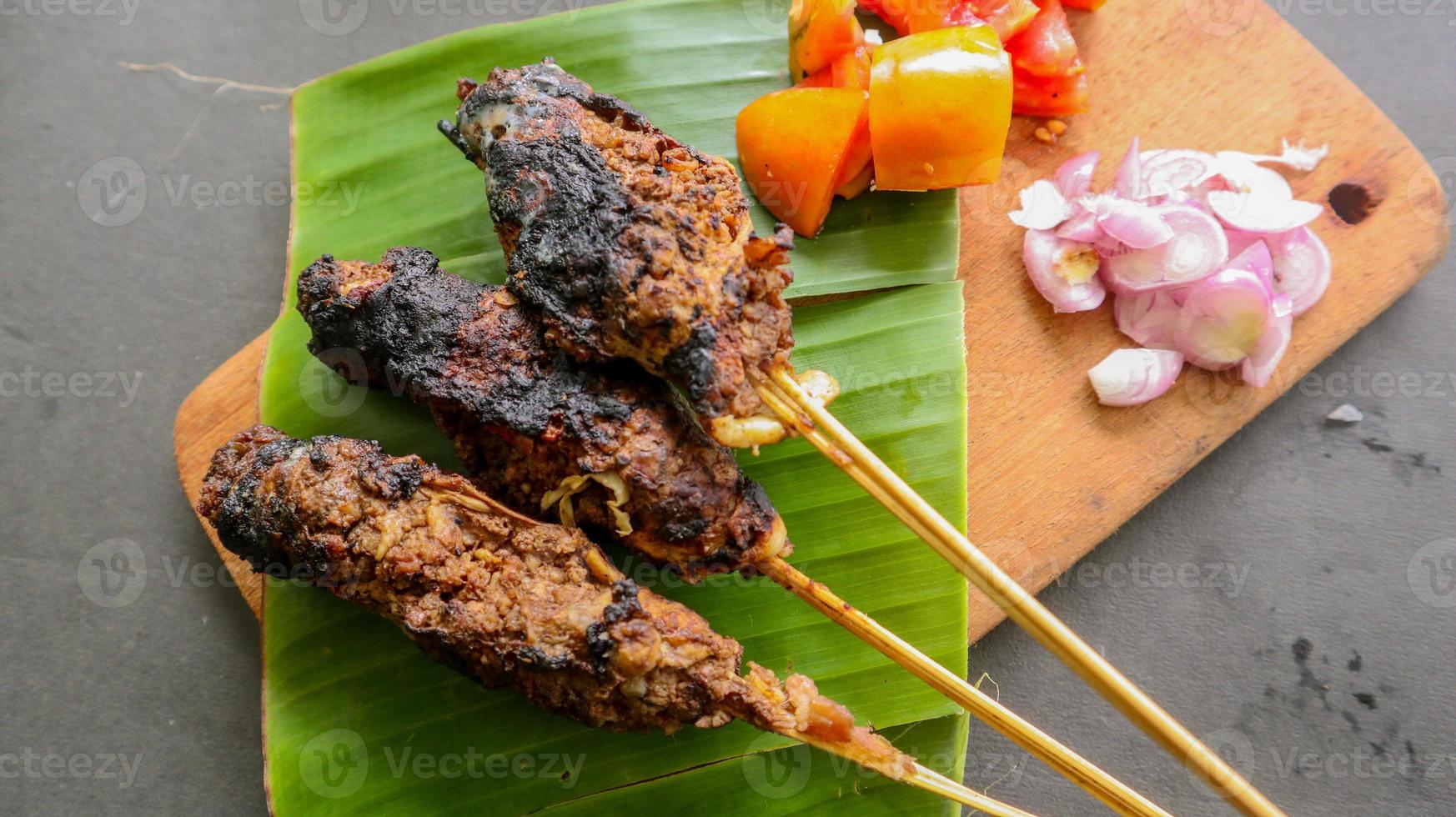 sate buntel or satay buntel is satay made from minced mutton wrapped in mutton fat and then grilled. seasoning with tomatoes, shallots, pepper, cabbage photo