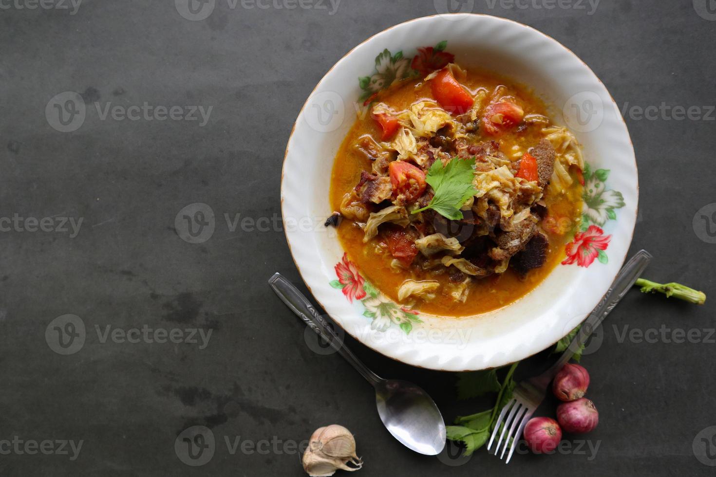 Goat Curry or gulai kambing, food from asia. Delicious goat meat curry served in a bowl.served with tomato, seasoning, celery and cabbage photo