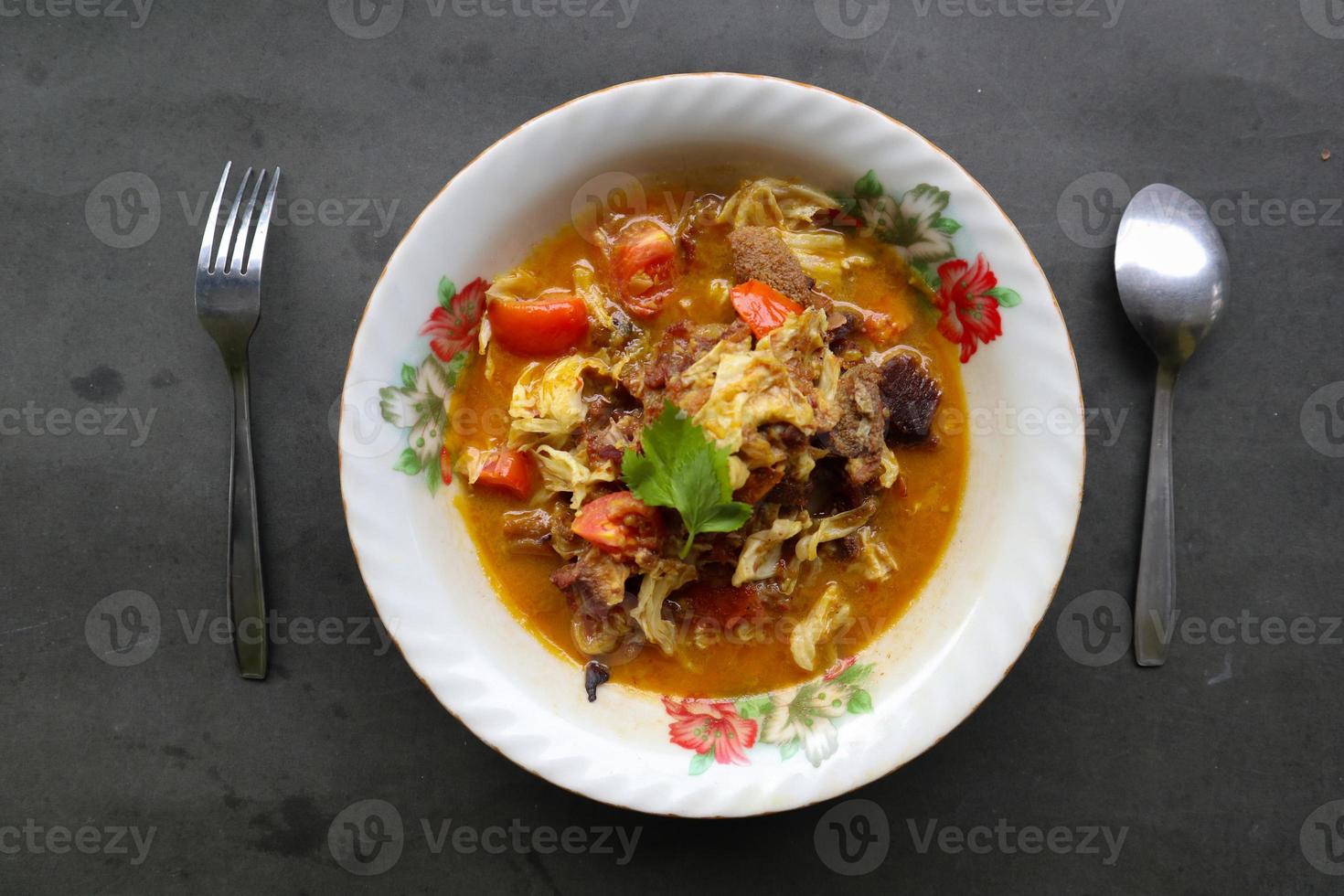 Goat Curry or gulai kambing, food from asia. Delicious goat meat curry served in a bowl.served with tomato, seasoning, celery and cabbage photo