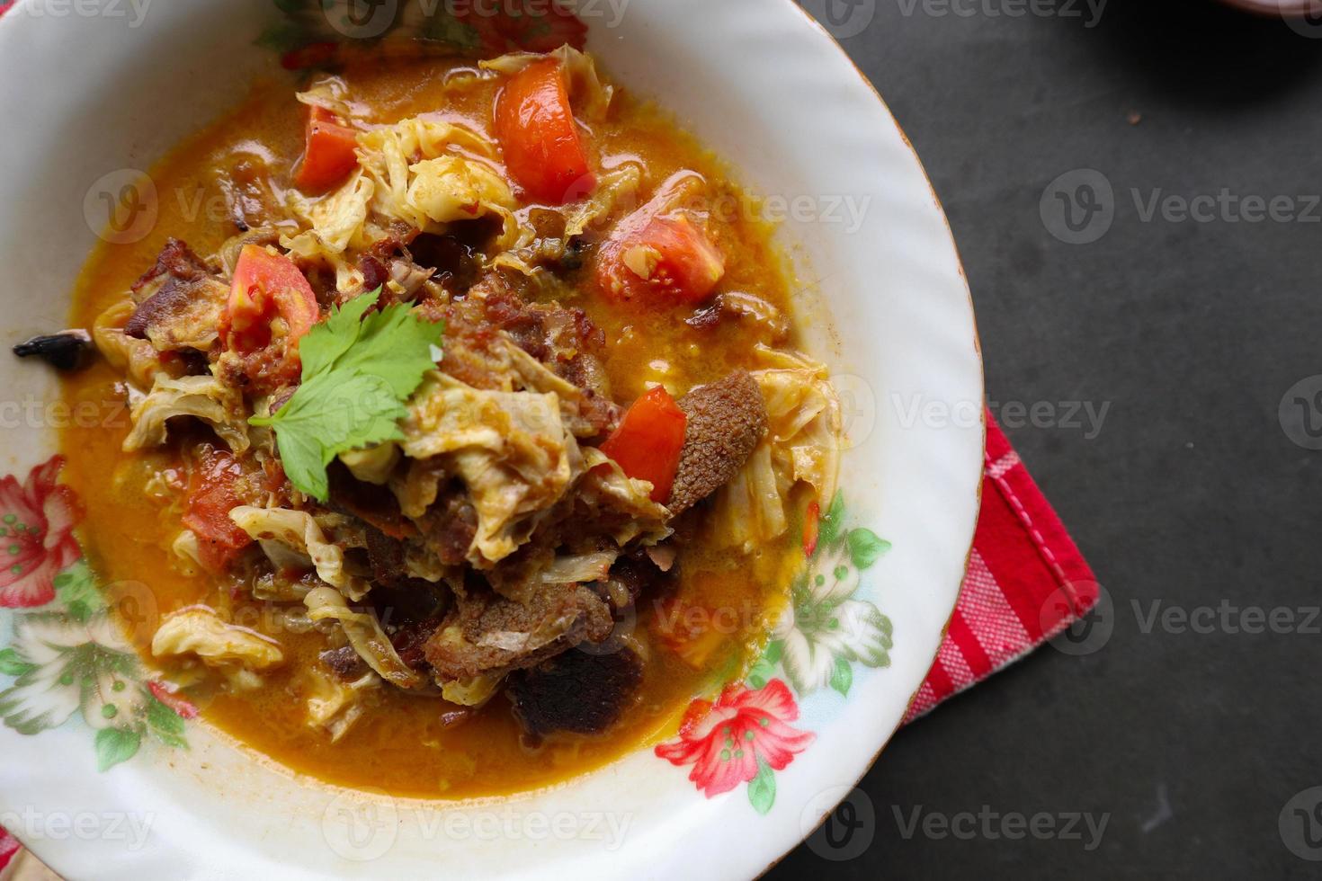 Goat Curry or gulai kambing, food from asia. Delicious goat meat curry served in a bowl.served with tomato, seasoning, celery and cabbage photo