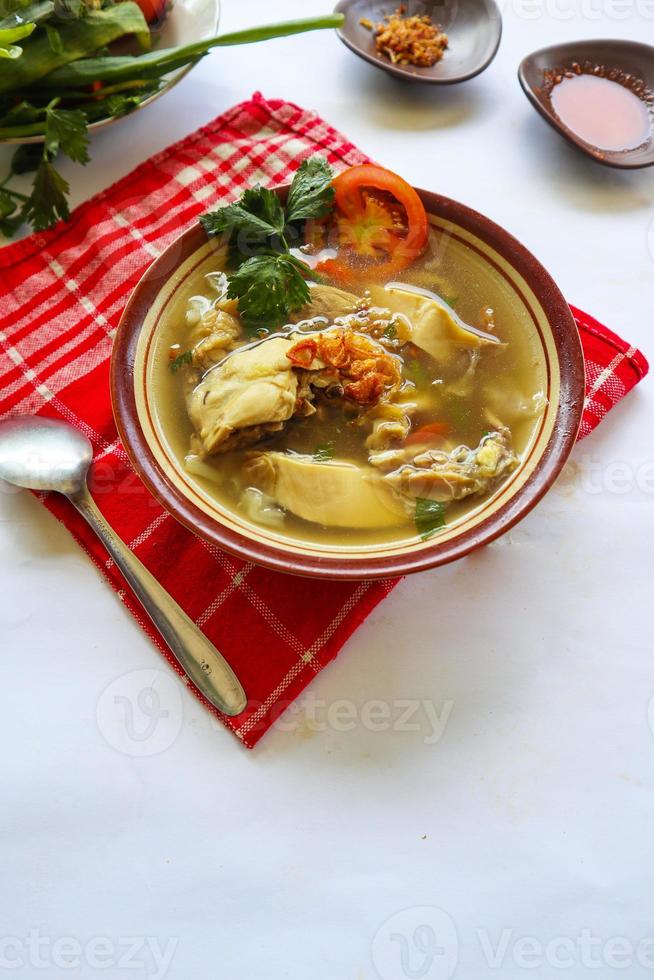 Chicken soup served with vegetables, tomatoes, celery in a bowl, spoon and fork. with black background photo