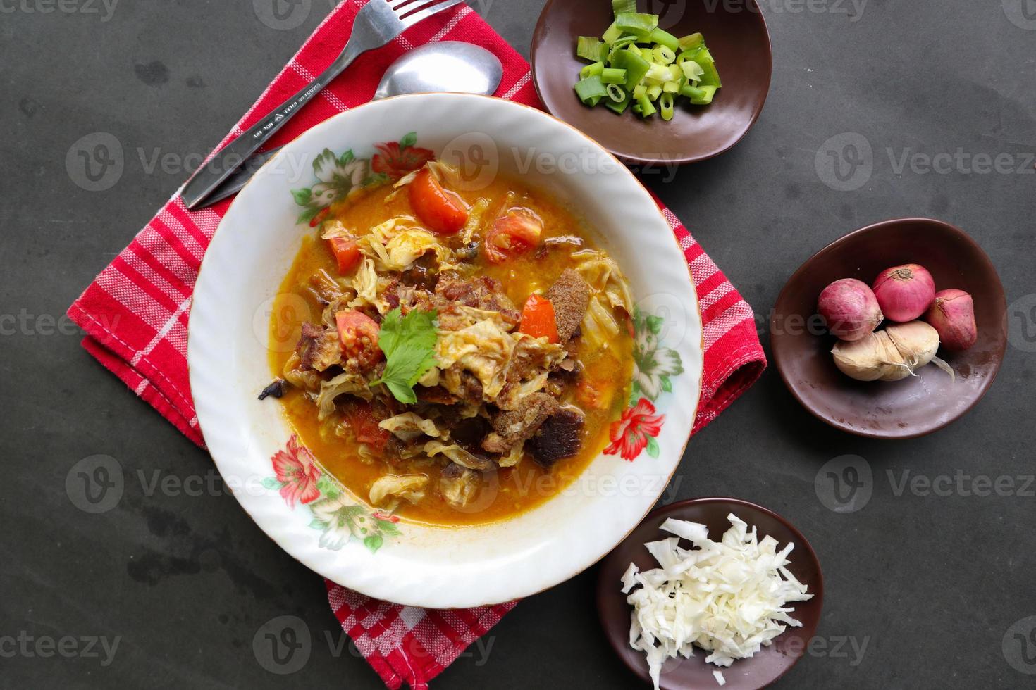 Goat Curry or gulai kambing, food from asia. Delicious goat meat curry served in a bowl.served with tomato, seasoning, celery and cabbage photo