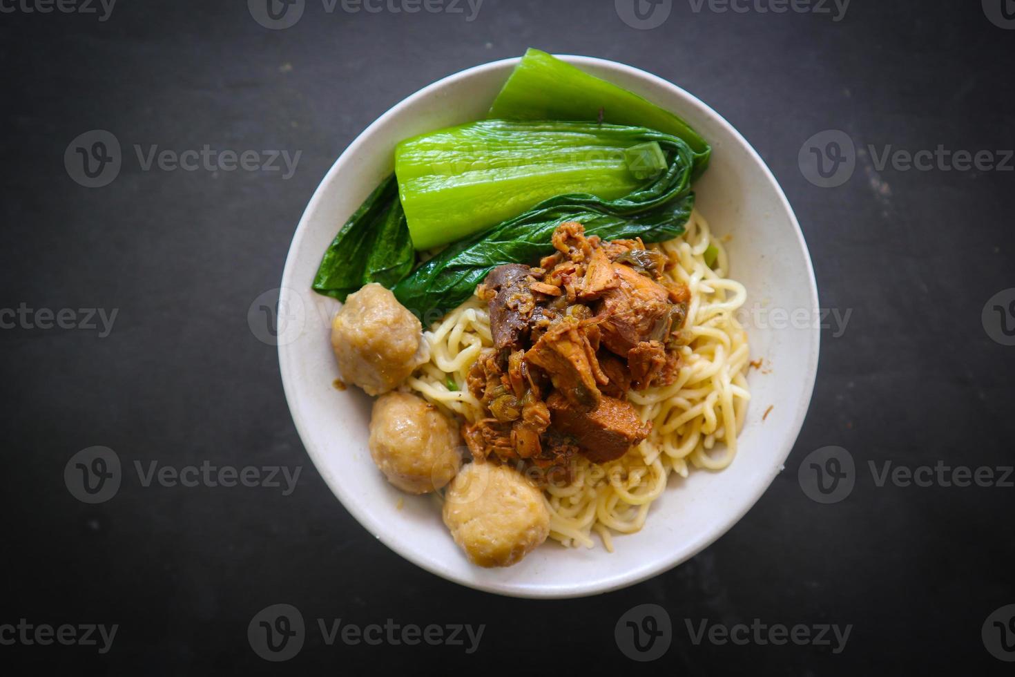 mie ayam or noodles chicken is traditional food from indonesia, asia made from noodle, chicken, chicken broth, spinach, sometimes with meatball. photo