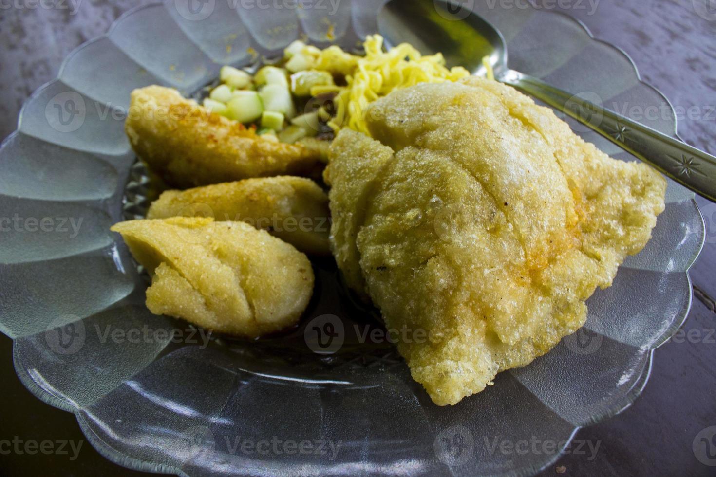 pempek IS fried fish and tapioca , cucumber slices, yellow noodles served with sweet and sour sauce called vinegar sauce or vinegar sauce. served on glass photo
