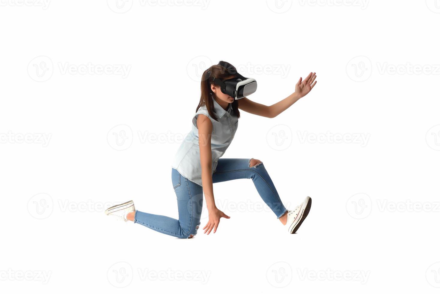 Pretty cute excited female in VR headset looking up and trying to touch objects in virtual reality photo