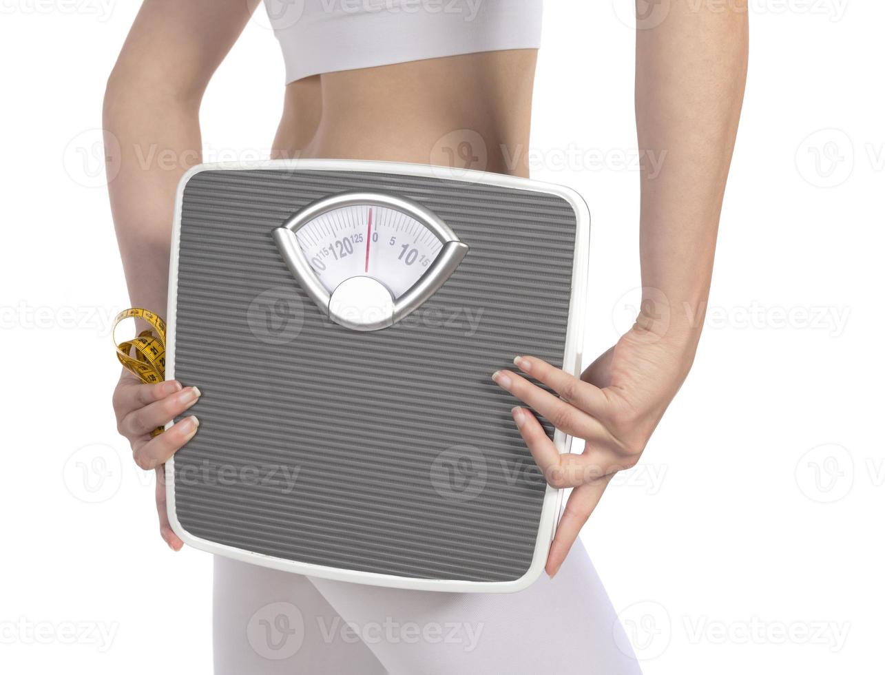 Female model holding scale and measuring tape over white background photo