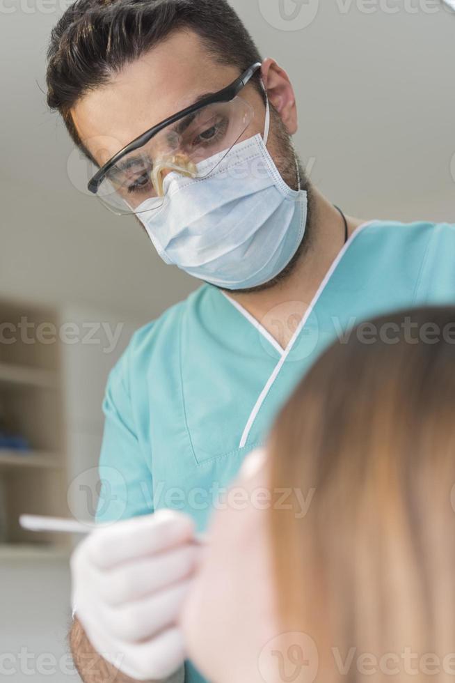 dentista curando los dientes del paciente llenando la cavidad. dentista que trabaja con equipo profesional en la clínica. foto