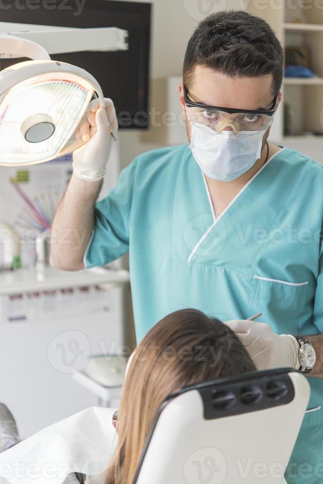 dentist curing patient's teeth filling cavity. Dentist working with professional equipment in clinic. photo