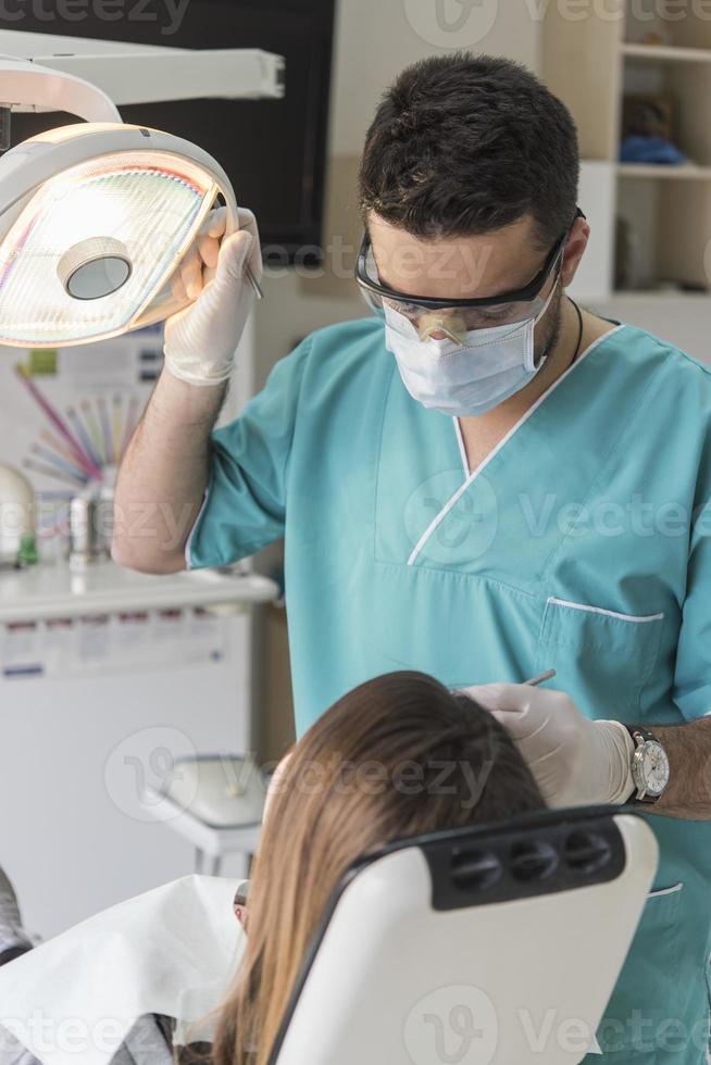 dentist curing patient's teeth filling cavity. Dentist working with professional equipment in clinic. photo