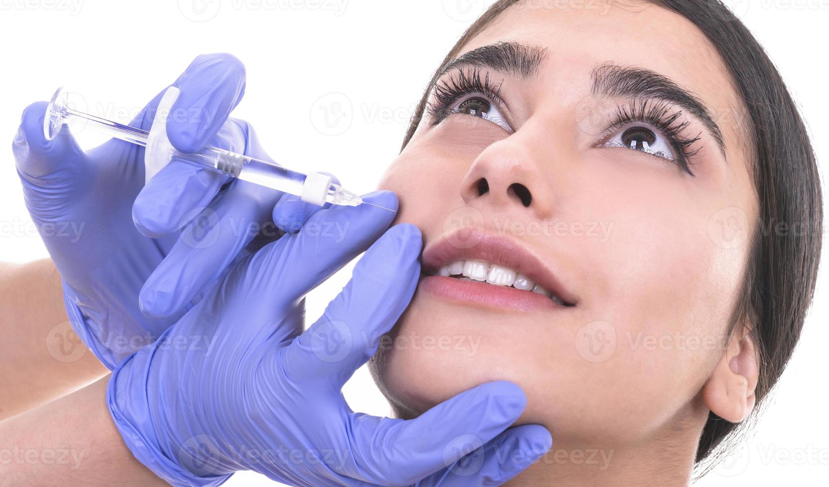 mujer joven recibe inyección de botox en sus labios. mujer en salón de belleza. clínica de cirugía plástica. foto