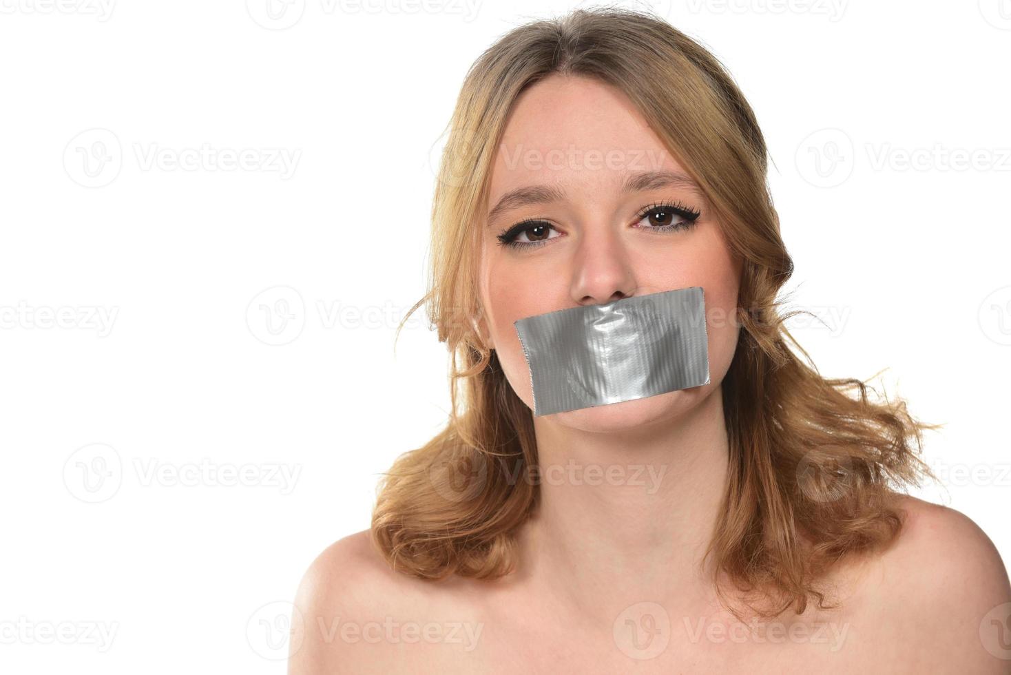 scared young woman with tape over her mouth. photo