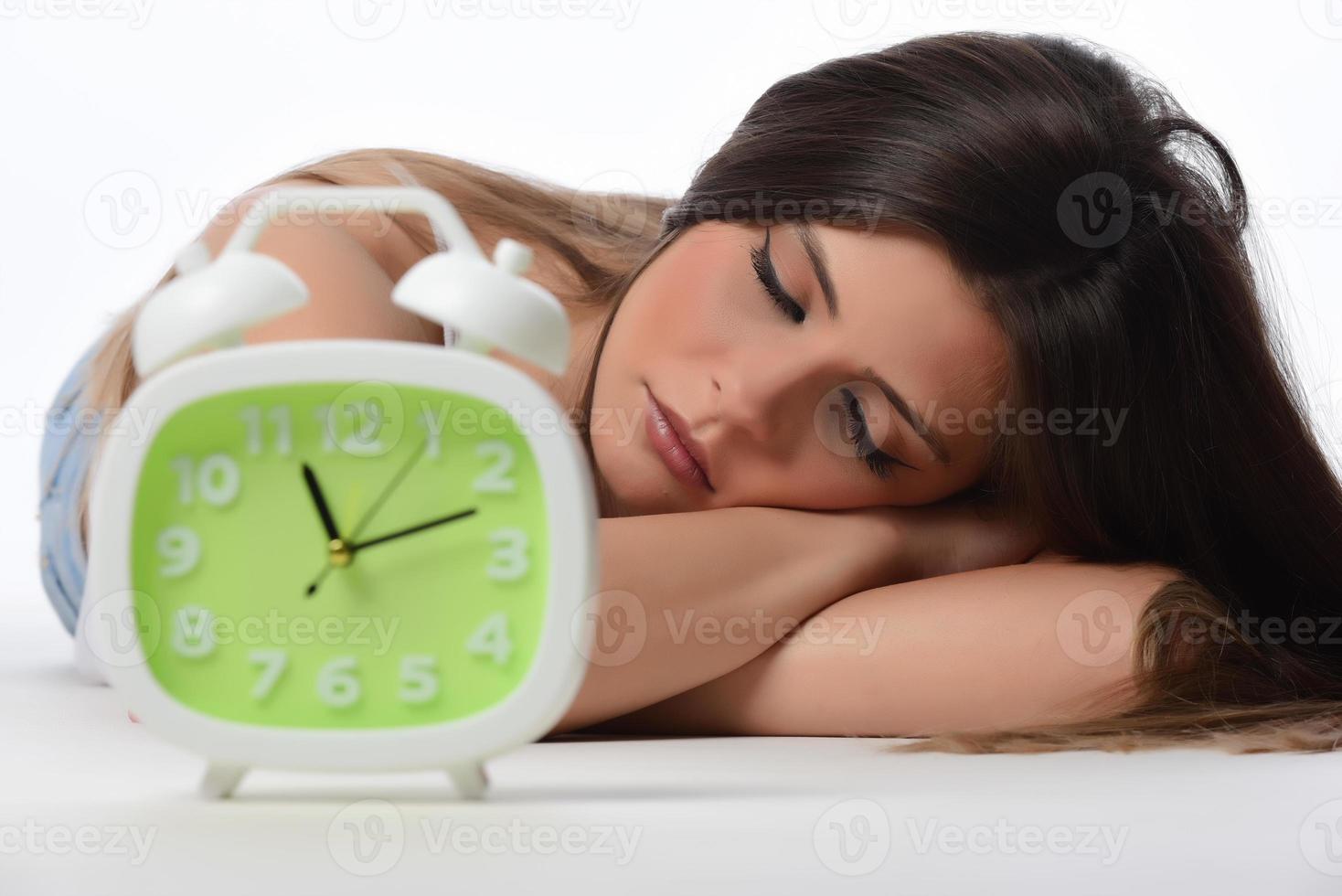 Beautiful sleeping woman resting in bed with alarm clock ready to wake her in the morning. photo