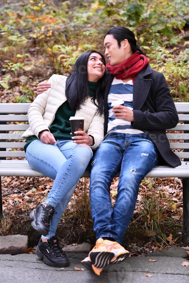 Mixed couple In park enjoying each other and drinking coffee photo