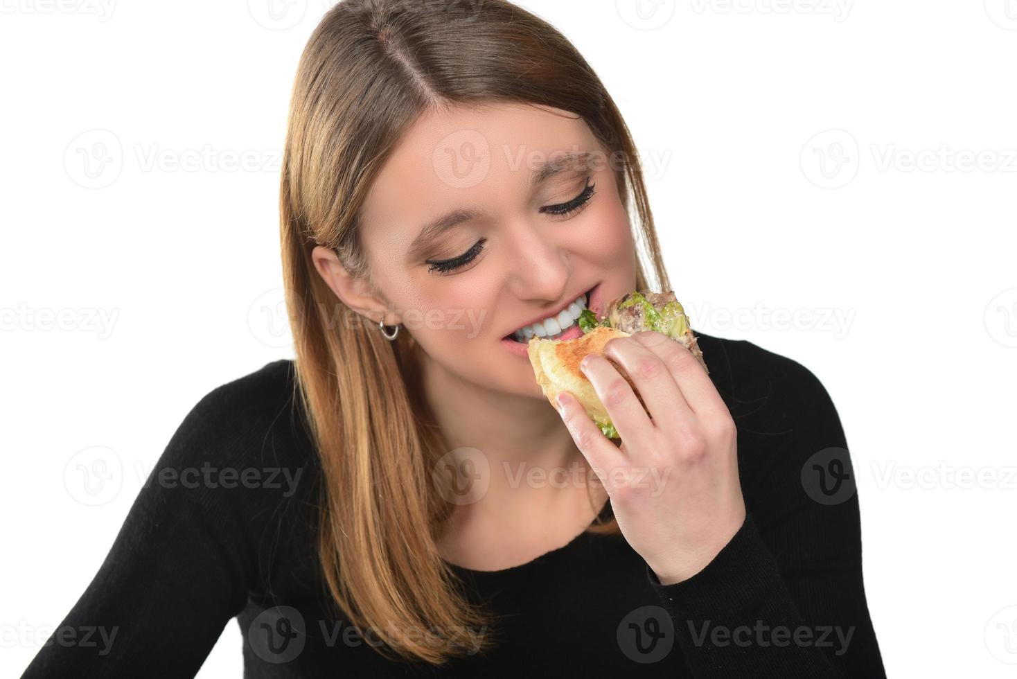 retrato de una hermosa joven divertida comiendo hamburguesas. foto