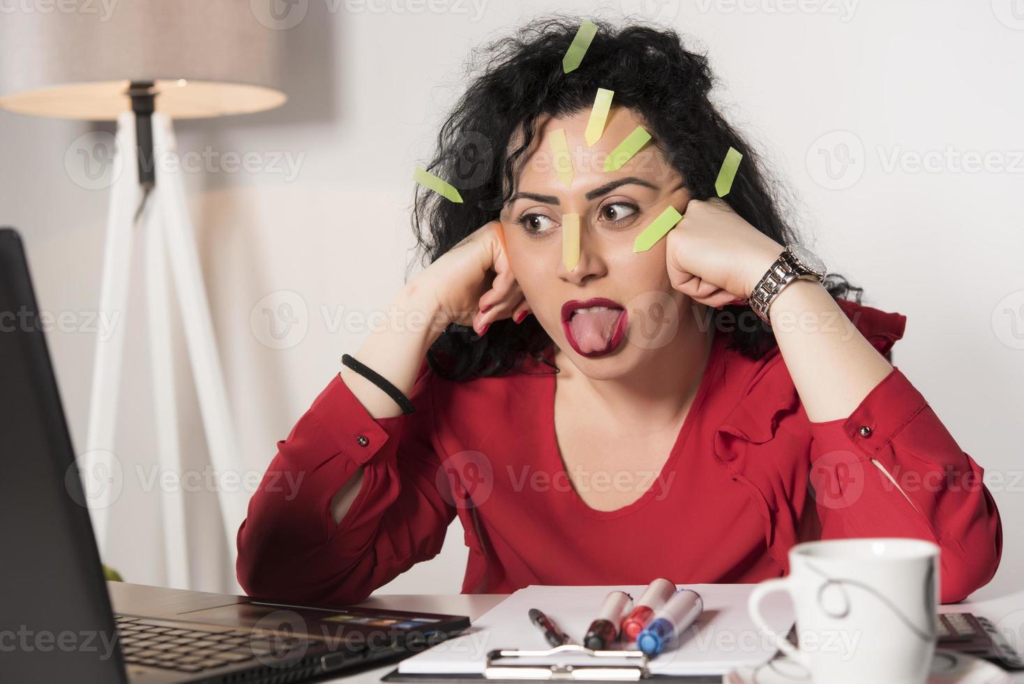 Pretty female model with a lot of post it notes working in her office. photo