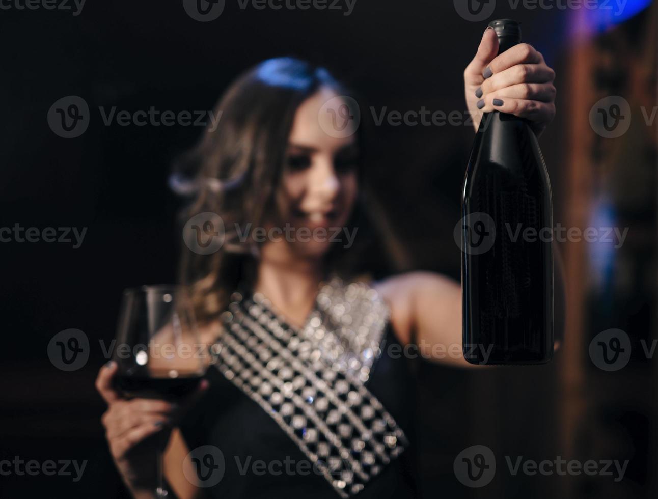 female fashionable model holding glass and bottle of wine. Woman driking wine. photo