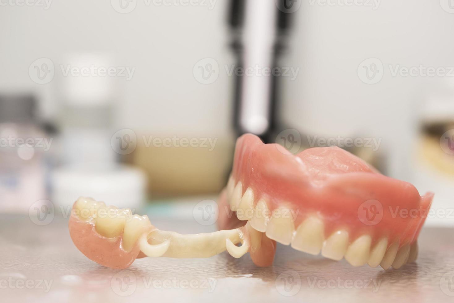 Dental prosthesis, dentures, prosthetics work. Prosthetics hands while working on the denture, false teeth, a study and a table with dental tools photo